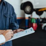 Auto mechanic taking sign on document from customer