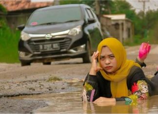 Cara unik sindir pihak tertentu, wanita ini ‘posing’ di jalan rosak dan berlumpur