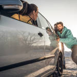 Two young men helping a woman who had a vehicle breakdown on a winter day.